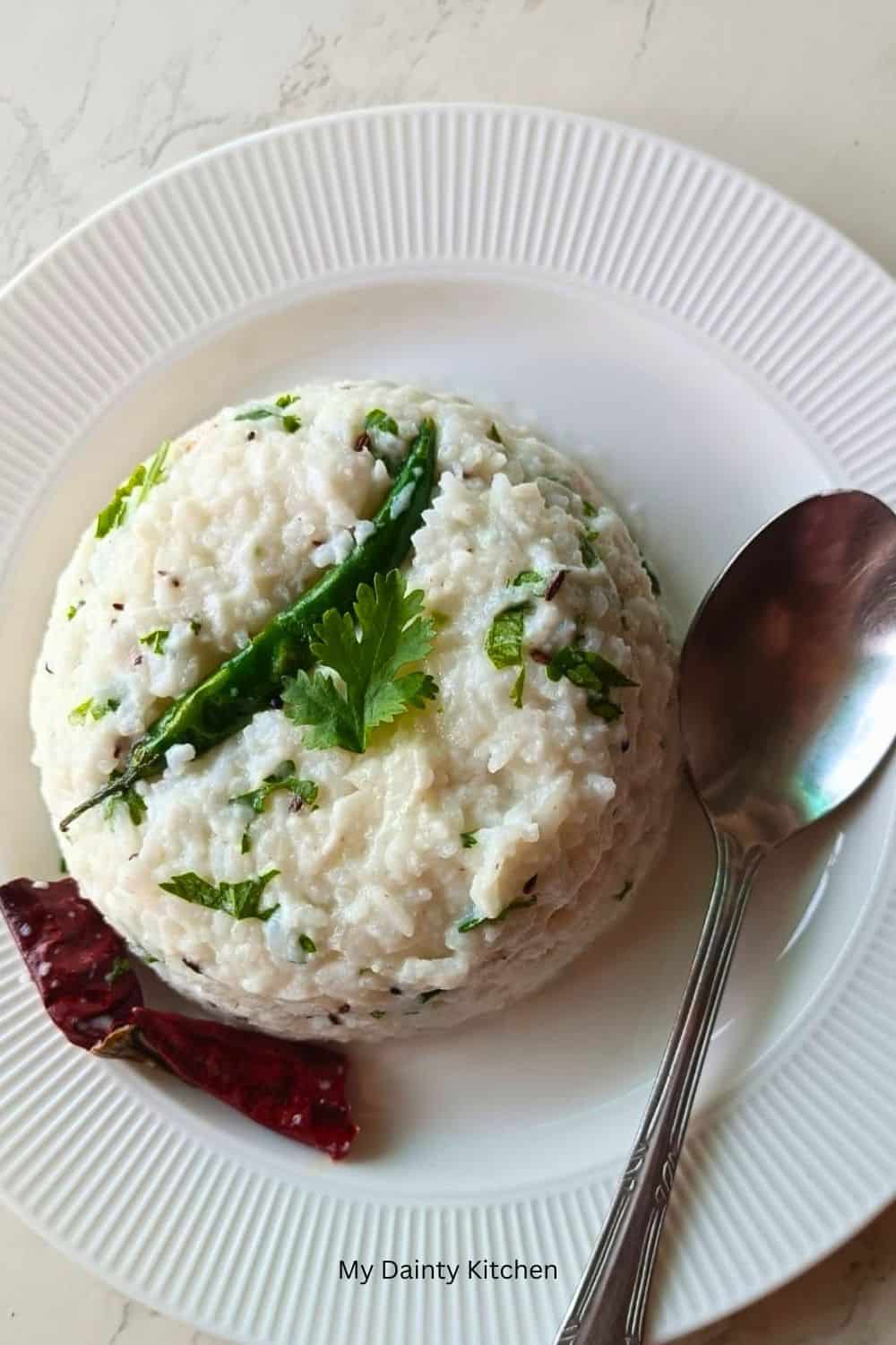 curd rice kept on a white round plate with a spoon